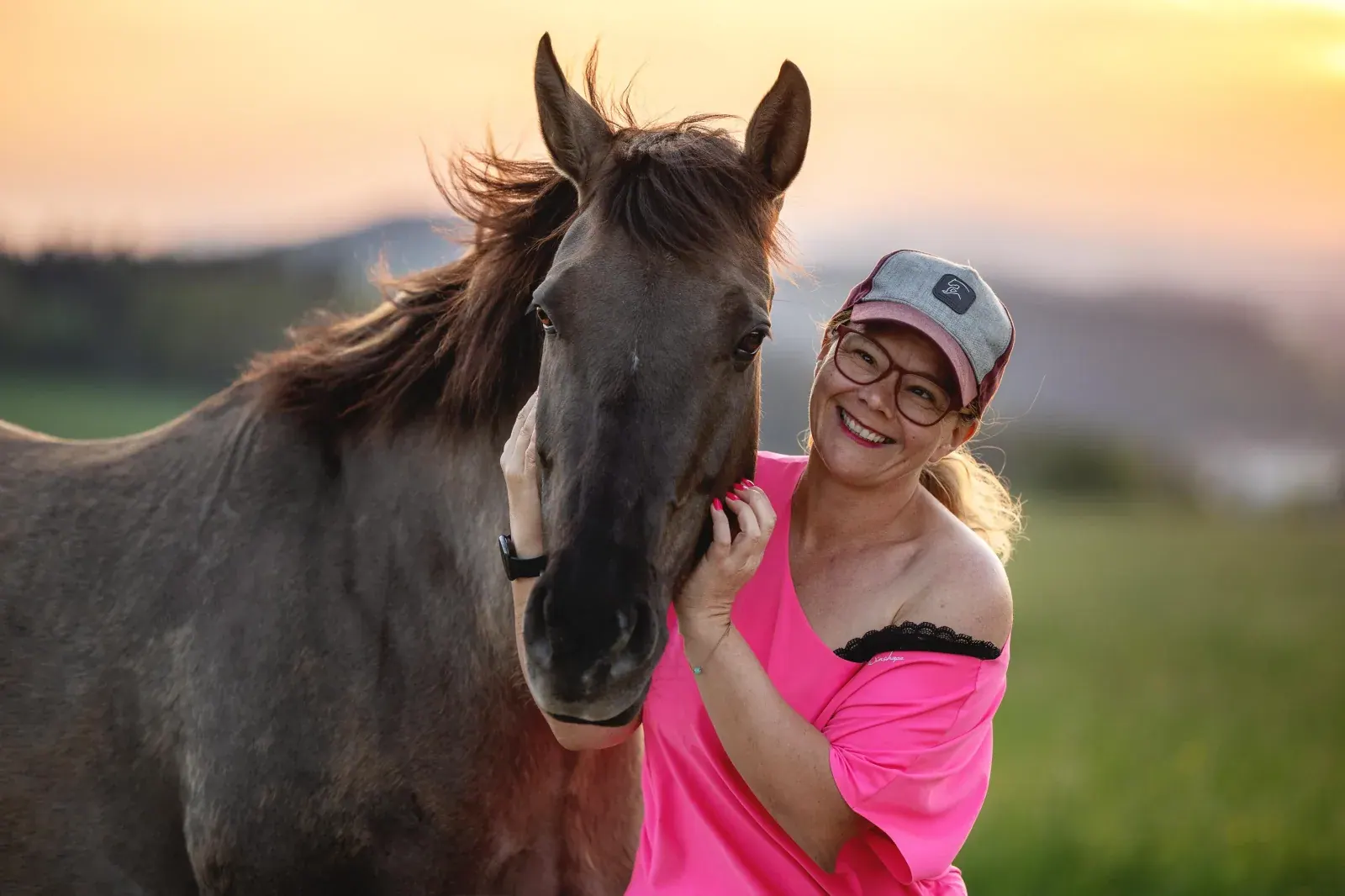 Yvonne Obermüller lacht mit einem Pferd im warmen Abendlicht