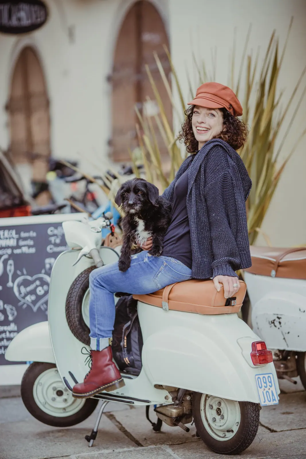 Unternehmerin mit Hund auf einer weißen Vespa