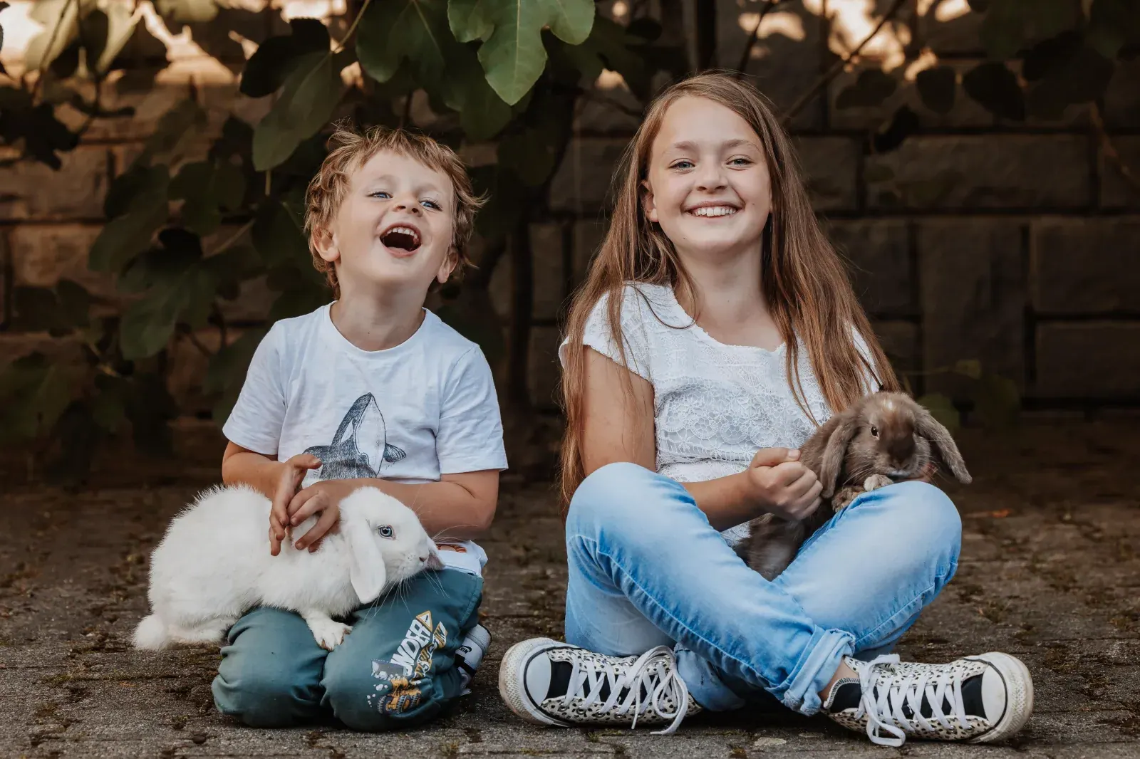 Zwei lachende Kinder mit weißen Hasen