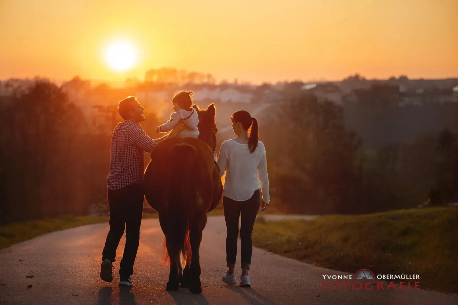 Familie mit Pferd beim Spaziergang im Abendlicht